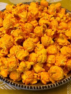 a bowl filled with yellow popcorn sitting on top of a tablecloth covered table cloth