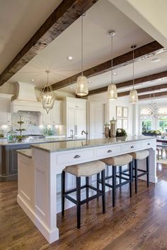 a large kitchen with an island and two stools next to it on a hard wood floor