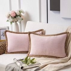 two pillows sitting on top of a couch next to a vase with flowers in it