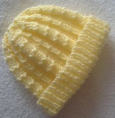 a yellow knitted hat laying on top of a white blanket