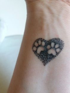 a black and white dog paw heart tattoo on the left side of her wrist,