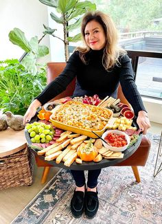 a woman sitting in front of a platter full of food