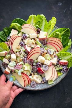 a plate with apples, grapes, and cheese on top of lettuce leaves