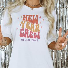 a woman wearing a new year's t - shirt with her hands in the air