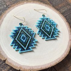 a pair of blue beaded earrings sitting on top of a piece of wood