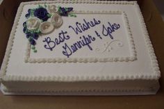 a cake with white frosting and blue flowers on it sitting in a cardboard box