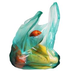 a plastic bag filled with fruit on top of a white table next to a banana and an apple