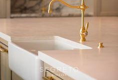 a golden faucet sits on top of a marble countertop in a kitchen