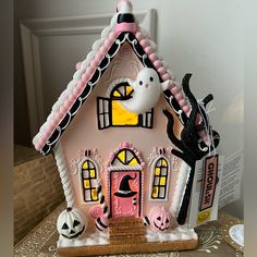 a pink and black gingerbread house decorated with halloween decorations