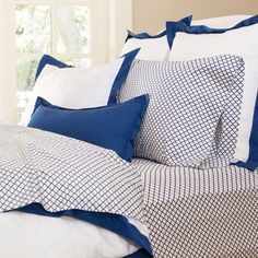 a bed with blue and white sheets, pillows and pillow cases on top of it