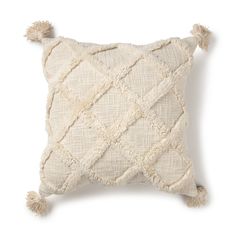 a white pillow with tassels on the front and back of it, sitting on a white surface