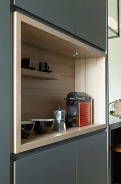 a kitchen with gray cabinets and black bowls on the counter top in front of an orange coffee maker