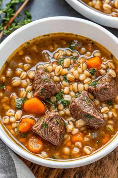 two bowls of beef and bean soup with carrots, parsley on the side