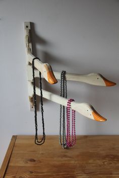 a wooden rack with necklaces hanging from it's sides on top of a table