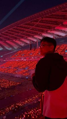 a man standing in front of a stadium filled with red lights