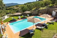 an outdoor swimming pool surrounded by lawn chairs and umbrellas