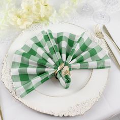 a green and white checkered napkin on a plate with silverware next to it