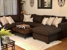 a living room filled with lots of furniture and pillows on top of a wooden floor