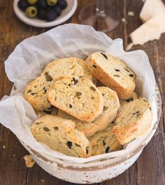 a bowl filled with bread and olives next to a glass of wine