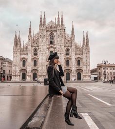 a woman sitting on top of a bench in front of a cathedral