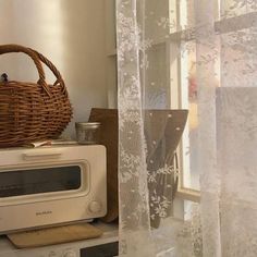 a basket sitting on top of a microwave next to a window