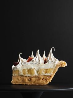 a piece of cake with bananas and whipped cream on top is sitting on a black table