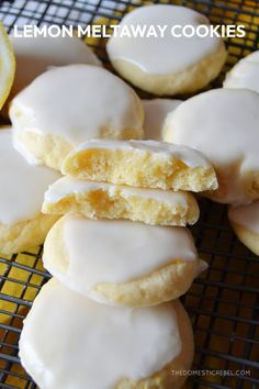 lemon meltaway cookies with white icing on a cooling rack next to an orange slice