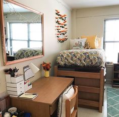 a bedroom with a bed, desk and mirror on the wall next to a window