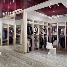 an open closet with clothes on hangers and chandeliers