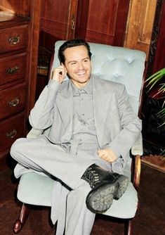 a man sitting in a chair talking on a cell phone and smiling at the camera