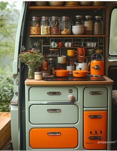 an orange stove top oven sitting inside of a green cabinet filled with pots and pans