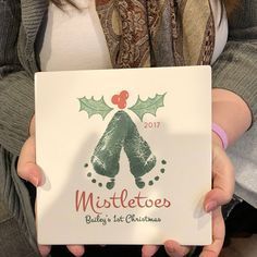 a woman holding up a christmas card with the word mistletoes written on it