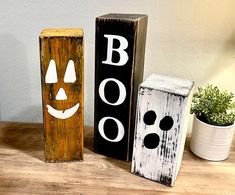 two wooden blocks with faces painted on them sitting on a table next to a potted plant