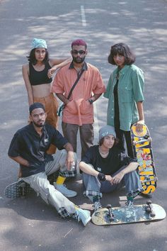 five children with skateboards standing in a row on a dirt road near dry grass