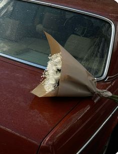 a bouquet of flowers is placed on the hood of a car's door window