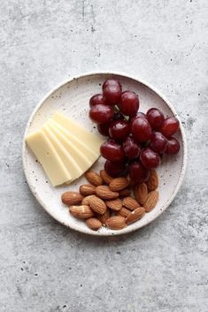 grapes, almonds and cheese on a white plate