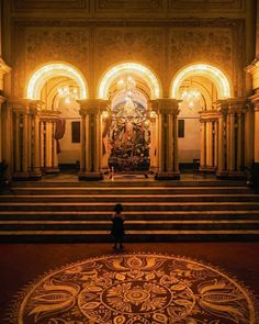 a person standing in the middle of a large room with many arches and lights on it