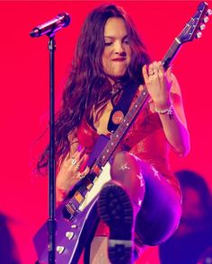 a woman with long hair playing an electric guitar