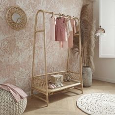 a baby's clothing rack in a room with pink wallpaper and white rugs