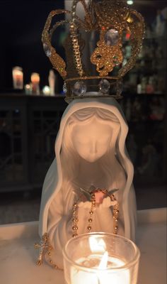 a candle is lit in front of a statue with a crown on top