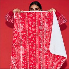 a woman is holding up a red and white blanket with snowflakes on it