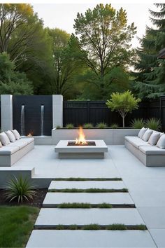 an outdoor fire pit surrounded by concrete steps and seating area with trees in the background