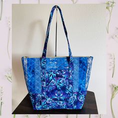 a blue tote bag sitting on top of a wooden table next to a white wall