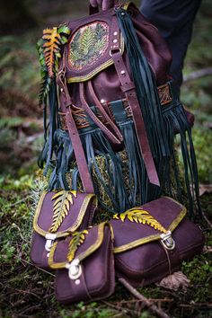 a handbag with fringes and leaves on it is sitting in the grass next to a pair of boots