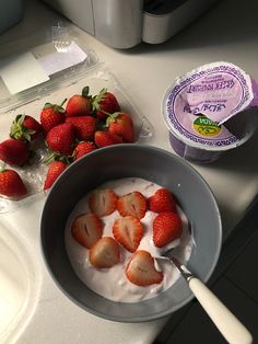 strawberries and yogurt in a bowl on a counter next to an ice cream container