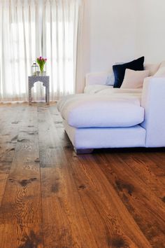 a living room with wood floors and white furniture