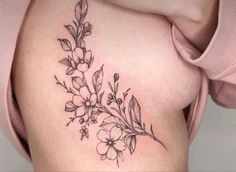 a woman's thigh with flowers and leaves tattoo on her side ribcage