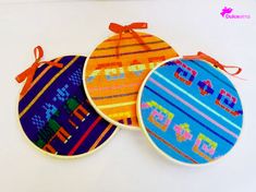 three colorful embroidered ornaments on white surface