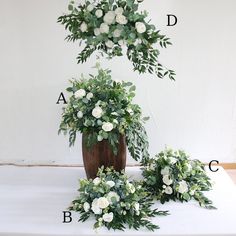 three potted plants with white flowers and green leaves are arranged in the shape of letters