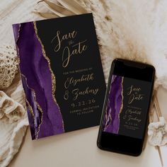 a cell phone sitting on top of a table next to a purple and gold save the date card